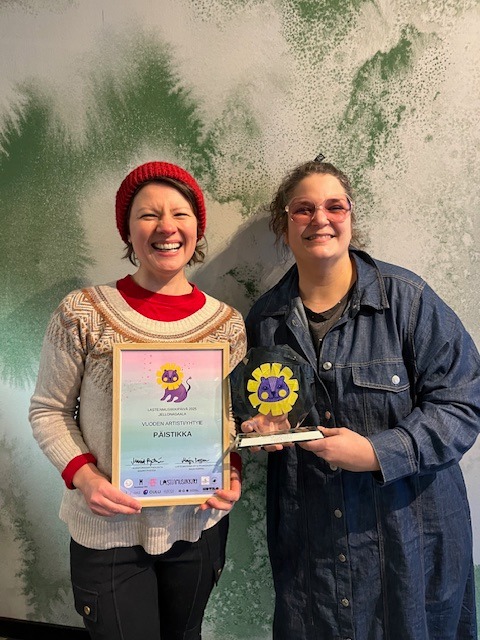 Päistikan Elina pokkaamassa Vuoden Yhtye -palkintoa 2025 puheenjohtajalta Maiju Kopralta. Kuva: Satu Alhojärvi